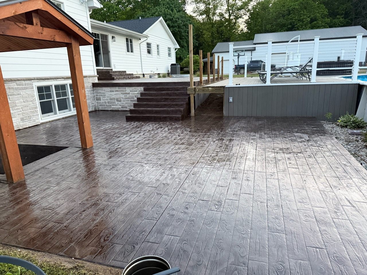 Wood-pattern concrete patio extending around a home and exterior steps