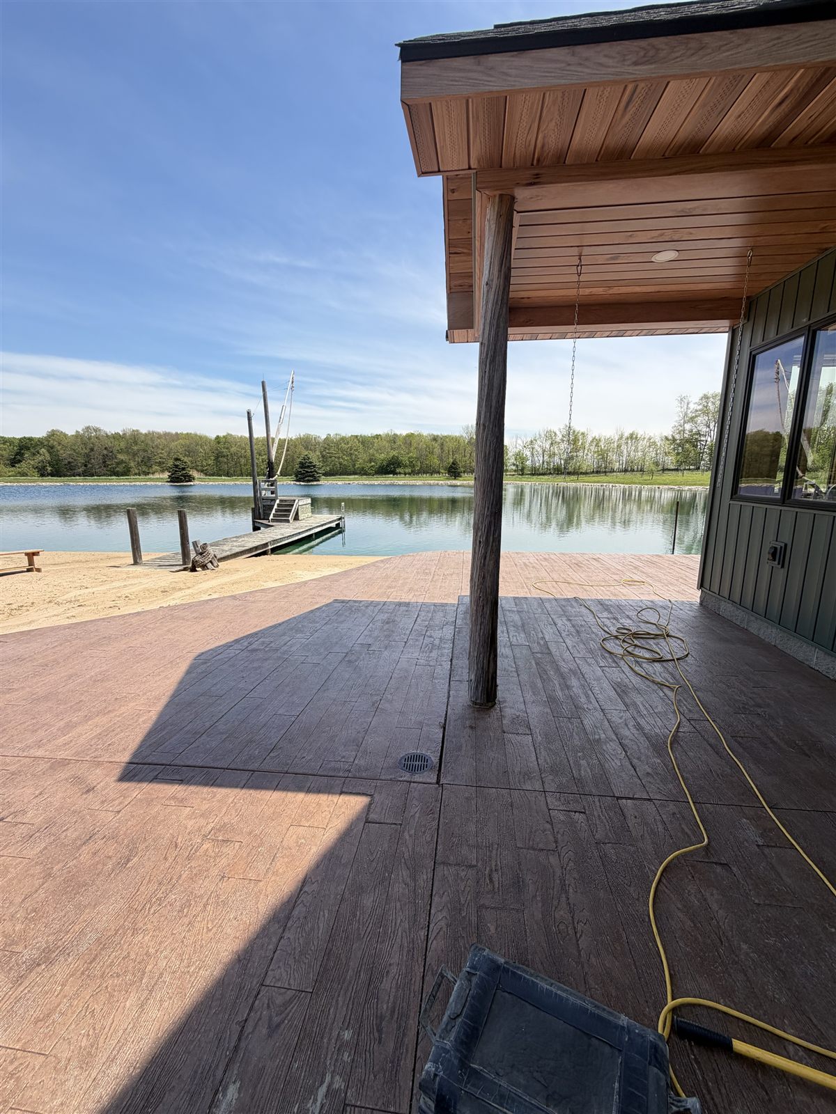 Wood plank stamp concrete beside a covered porch and pond
